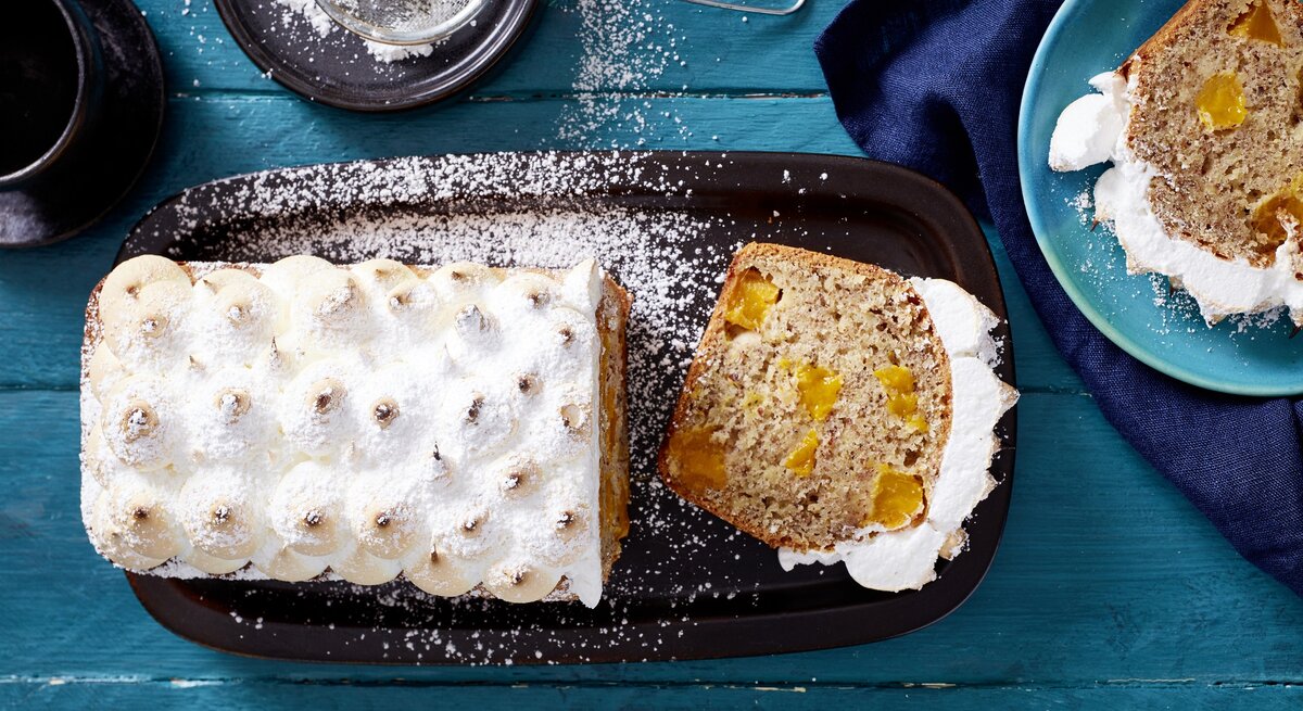 Der Mango-Baiser-Kuchen direkt von oben auf einem blauen Holztisch fotografiert.