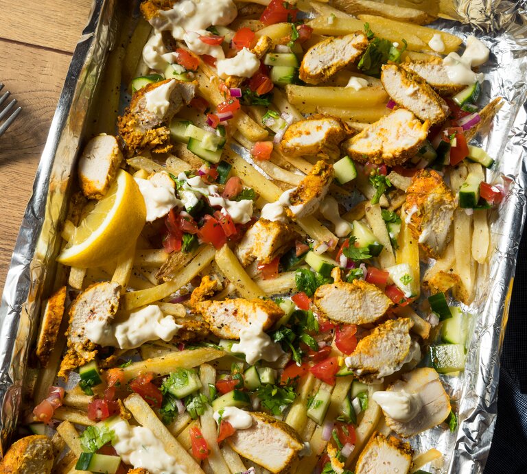 Ein-Blech-Shawarma mit Pommes und Salat angerichtet auf hölzernem mit blauem Tuch bedeckter Oberfläche.  | © Getty Images/bhofack2
