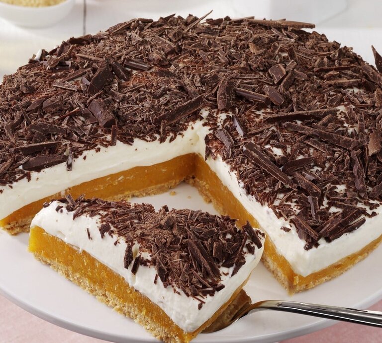 Auf einem Teller liegt eine Aprikosen-Joghurt-Torte ohne Backen. Sie ist mit Schokoraspeln bestreut. | © StockFood / StockFood Studios / Photoart