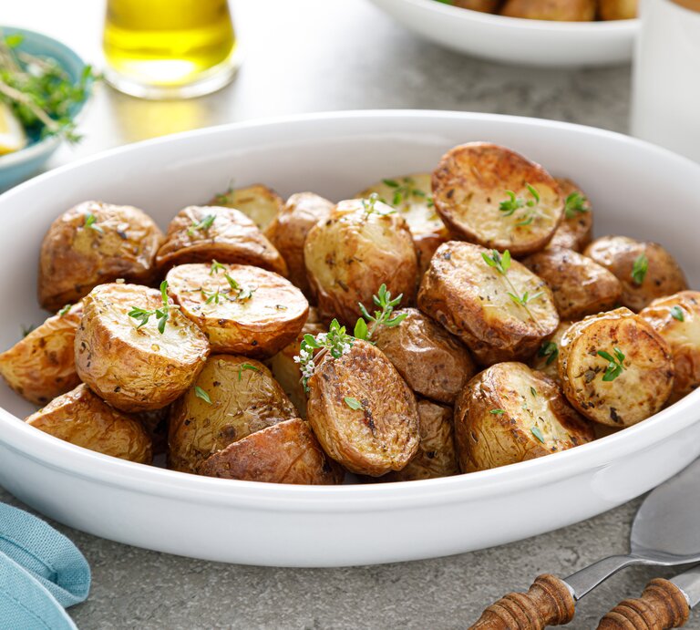Eine weiße Schüssel mit gebackenen Kartoffeln und Thymian.  | © Getty Images/YelenaYemchuk