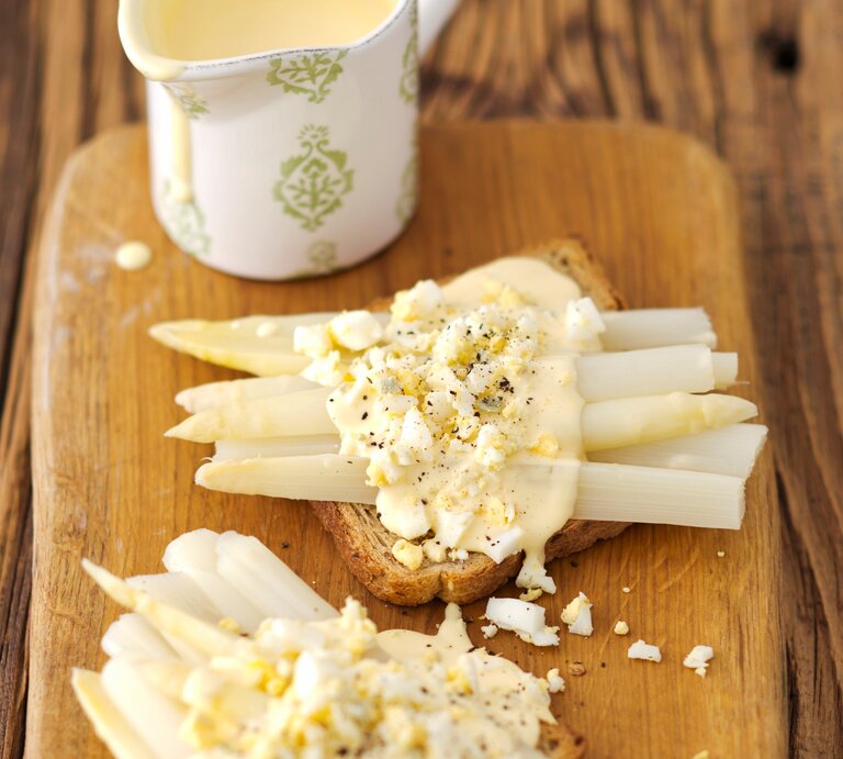 Toast mit Spargel und Eier-Soße auf Holzbrett serviert. | © StockFood/ Castilho, Rua