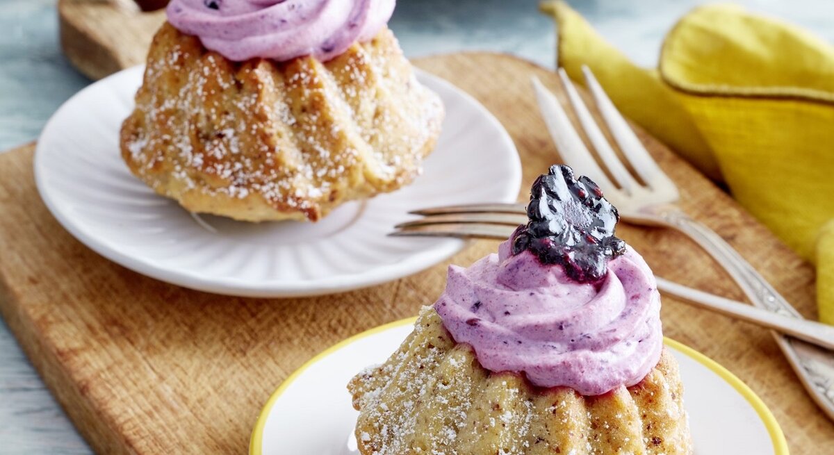 Auf zwei Tellern stehen je ein Apfelmus-Mini-Gugelhupf. Sie sind mit einer Creme und Brombeeren verziert. 