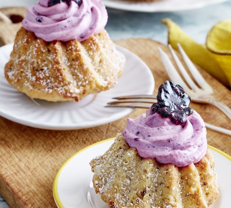 Auf zwei Tellern stehen je ein Apfelmus-Mini-Gugelhupf. Sie sind mit einer Creme und Brombeeren verziert.  | © EAT CLUB / Isabell Triemer
