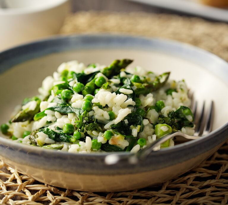 Ein Teller veganes Spargelrisotto mit Erbsen und Spinat, darin liegt eine Gabel. | © Getty Images/ haoliang