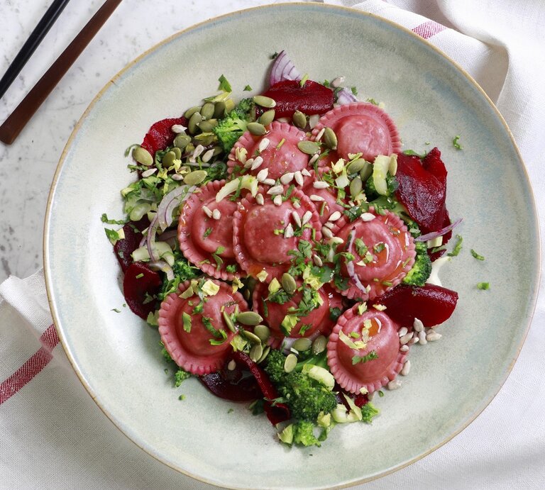 Salat mit Rote-Bete-Tortellini, Zwiebeln, frischer Rote Bete, Brokkoli, Kernen und Kräutern, serviert in einer hellen Schale auf einem Marmortisch, von oben fotografiert.  | © StockFood / wawrzyniak.asia