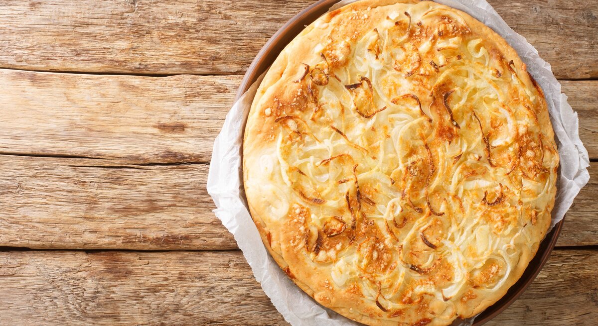 Eine Käsepizza auf einem Holztisch direkt von oben fotografiert.