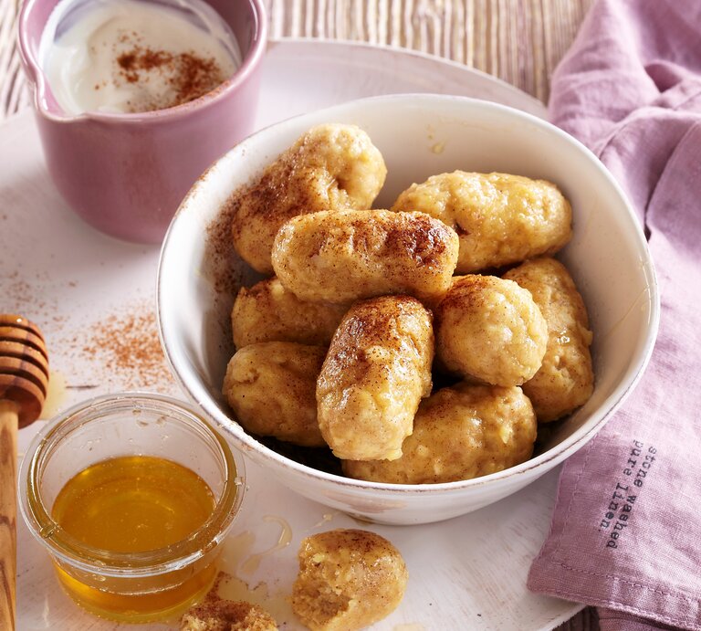 In einer weißen Schüssel liegen saftige Vanille-Apfel-Knödel. Sie sind mit Honig und Zimt verfeinert.  | © StockFood / Profimedia