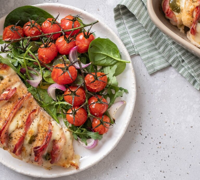 Mehrere Teller mit dem Fächerhähnchen und Kirschtomaten aus dem Ofen. Der Untergrund ist hellgrau und hellgrün-weiß gestreifte Tischdecken liegen um die Teller. | © Shutterstock/ Elena Shashkina