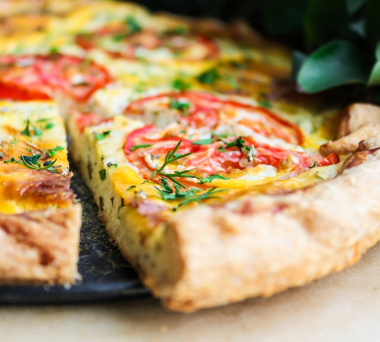Frühstückspizza auf einem Teller. Das Ganze auf einem hölzernen Untergrund.  | © Getty Images / Anna Kurzaeva