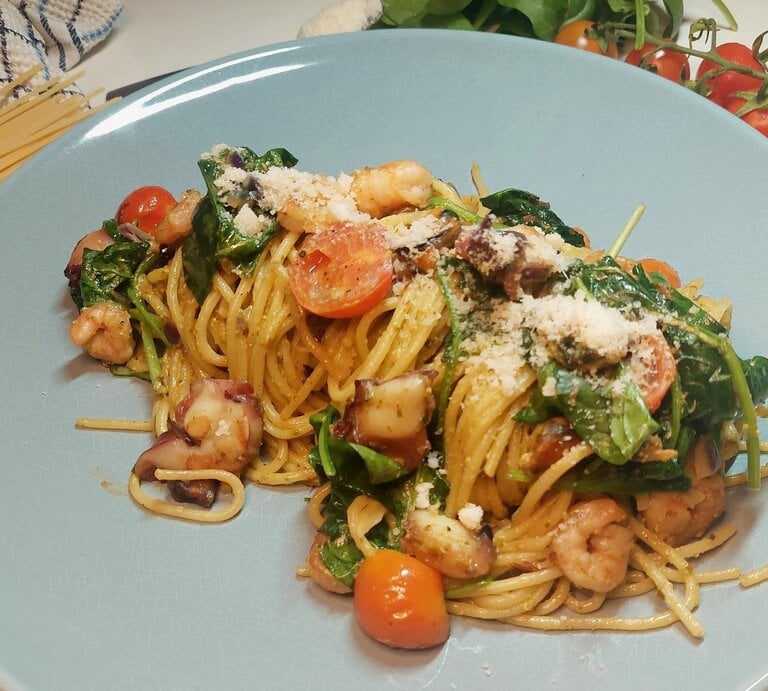 Blauer Teller mit den Zitronenspaghetti und Meersfrüchten. Im Hintergrund Nudeln Tomaten und Zitronen. | © EAT CLUB/ Felix Scheel
