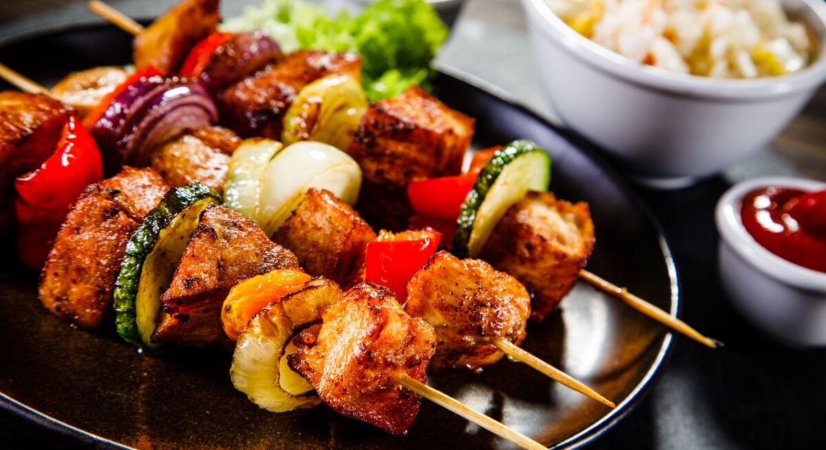 Saftig-zarte Schweinefiletspieße mit Gemüse frisch gegrillt auf dem Teller.