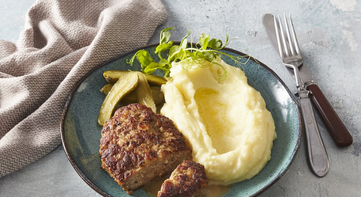 Butterfrikadellen mit Kartoffelpüree auf Teller serviert.