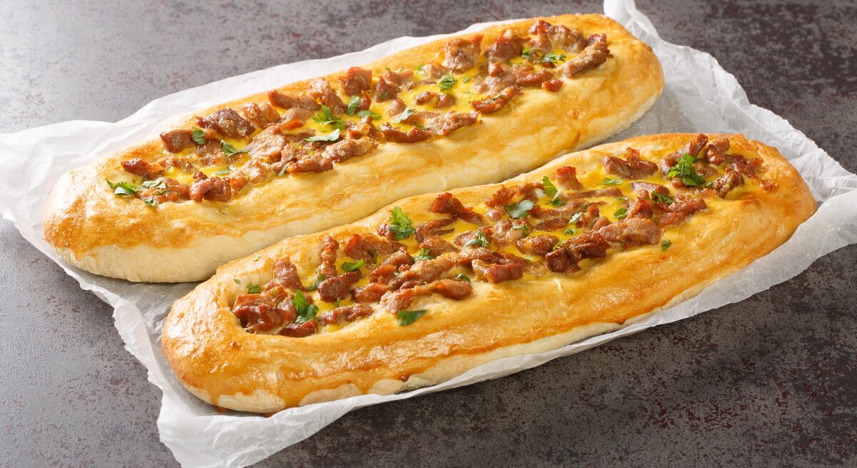 Pastrmajlija mezedonische Pizzabaguettes auf Küchenkrepp auf Steintisch. Draufsicht.