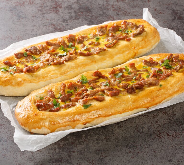 Pastrmajlija mezedonische Pizzabaguettes auf Küchenkrepp auf Steintisch. Draufsicht. | © Getty Images / ALLEKO