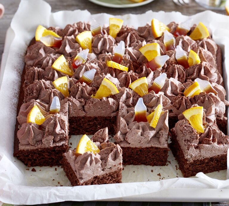 Auf einem Blech ist ein  Limo-Kuchen gebacken. Er ist mit Cola Fruchtgummis und Orangenstücken belegt.  | © EAT CLUB / Isabell Triemer