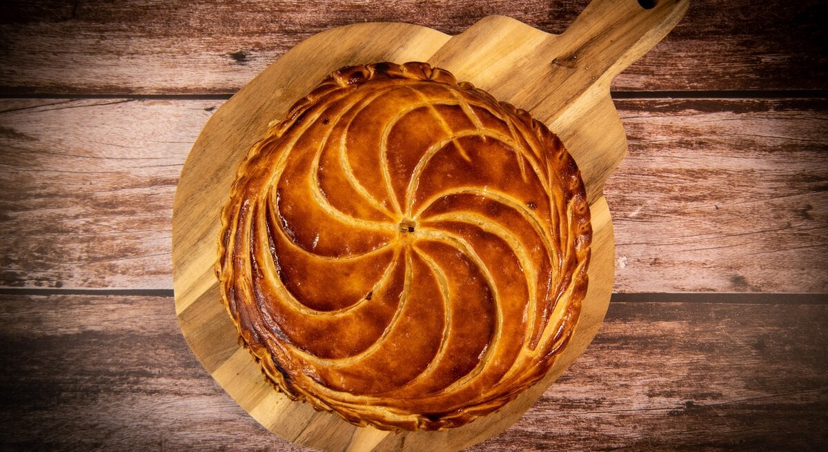 Galette de Rois auf Holzbrett und dunklem Untergrund. Draufsicht.