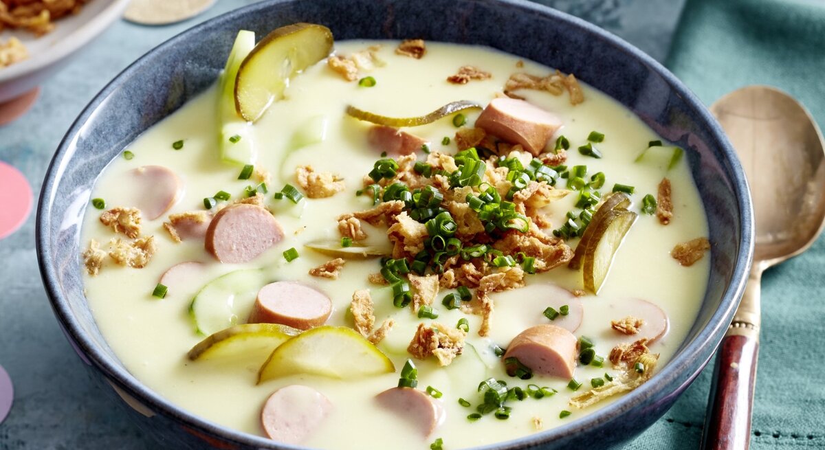 In einer Schüssel ist eine Hotdog-Suppe angerichtet. Sie ist mit Schnittlauch und Röstzwiebeln verfeinert.