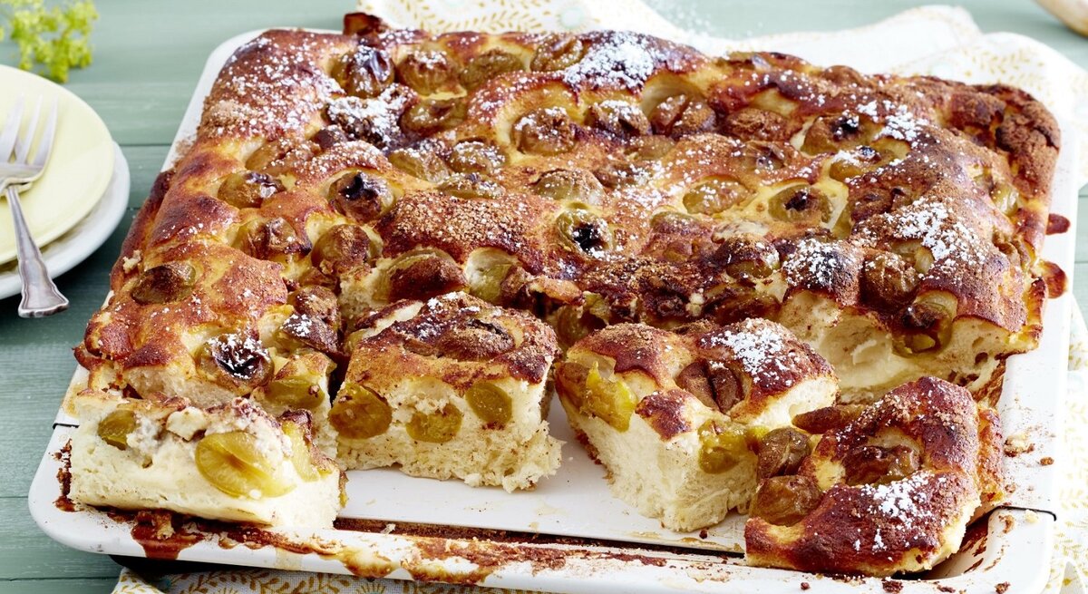 Auf einem Backblech liegt ein Mirabellen-Blechkuchen. Er ist mit Puderzucker bestreut. 