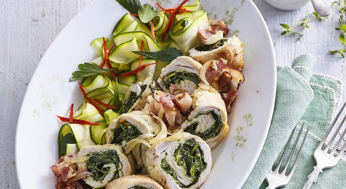 Gefüllte Putenröllchen mit Spinat und Kräuterpesto,  gehobelte Zucchini, frischer Petersilie, dünn geschnittener, Chili / zwei Gabeln / eine kleine runde Form mit einer Kräutersauce
