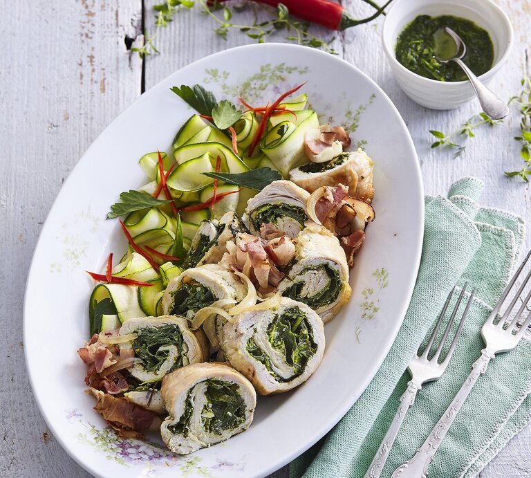 Gefüllte Putenröllchen mit Spinat und Kräuterpesto,  gehobelte Zucchini, frischer Petersilie, dünn geschnittener, Chili / zwei Gabeln / eine kleine runde Form mit einer Kräutersauce | © StockFood / Profimedia