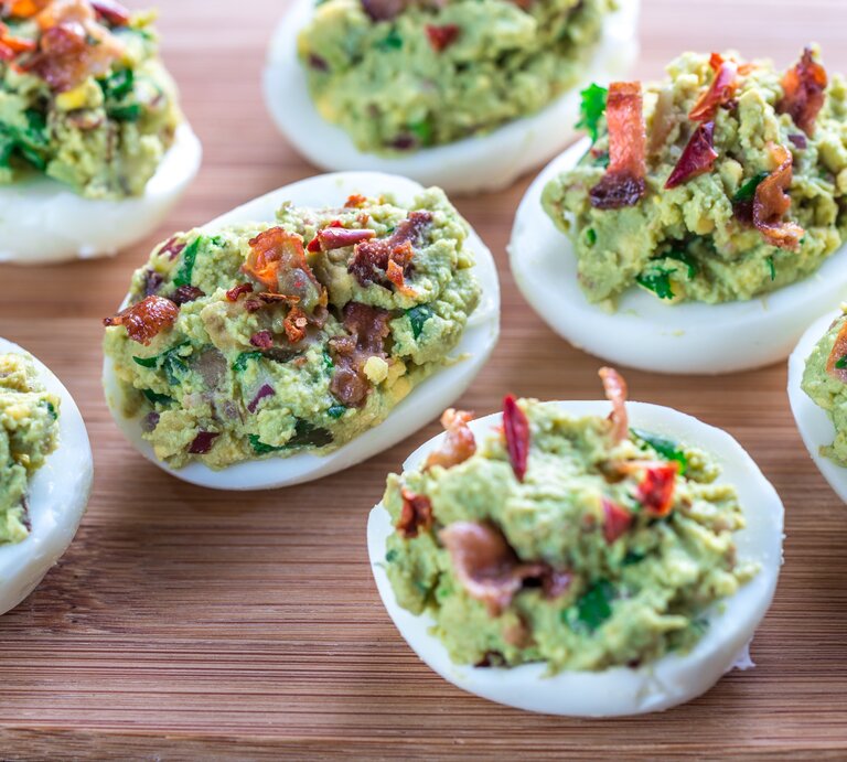 Sieben gefüllte Eier mit Avocado und Bacon auf Holzbrett. Aufnahme aus der Vogelperspektive. | © Alexander Prokopenko
