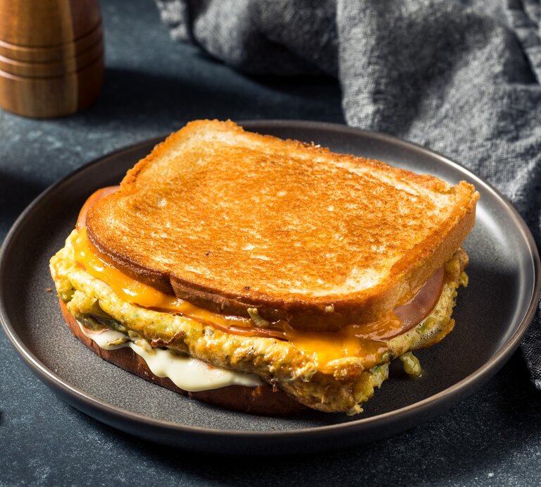 Ein zusammengeklapptes Toast auf einem grauen Teller und grauem Untergrund. | © Shutterstock/ bhofack2
