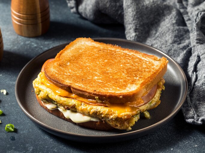 Ein zusammengeklapptes Toast auf einem grauen Teller und grauem Untergrund. | © Shutterstock/ bhofack2