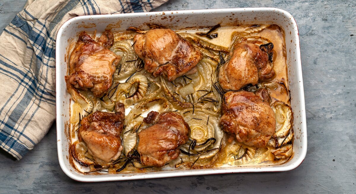 Eine ofenfeste Form mit Brathähnchen mit frischem Fenchel steht auf einem Tisch. Daneben liegt ein Handtuch.