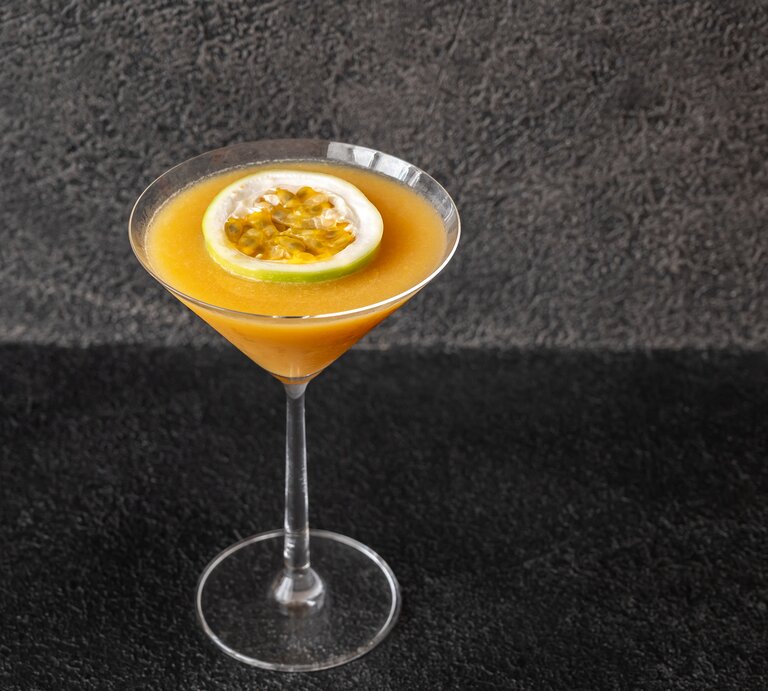 Martiniglas gefüllt mit orangefarbenem Cocktail vor dunkler Kulisse. | © Getty Images/AlexPro9500