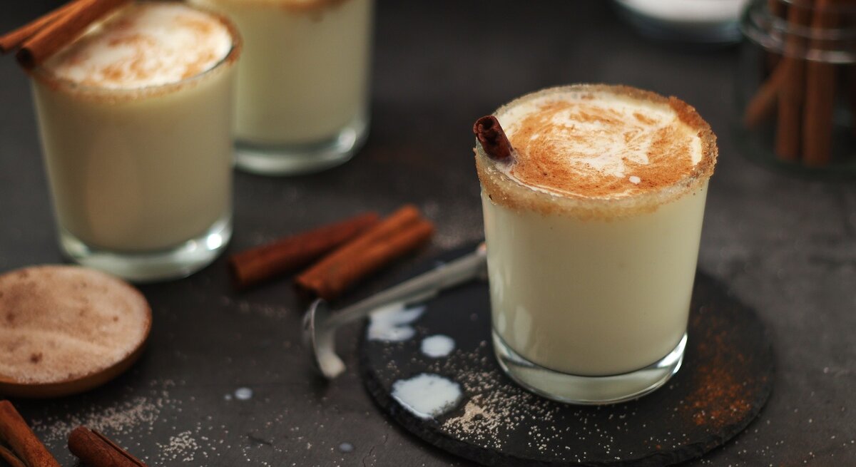 Drei Gläser mit dem Eierlikör-Milkshake auf einem dunklen Untergrund.