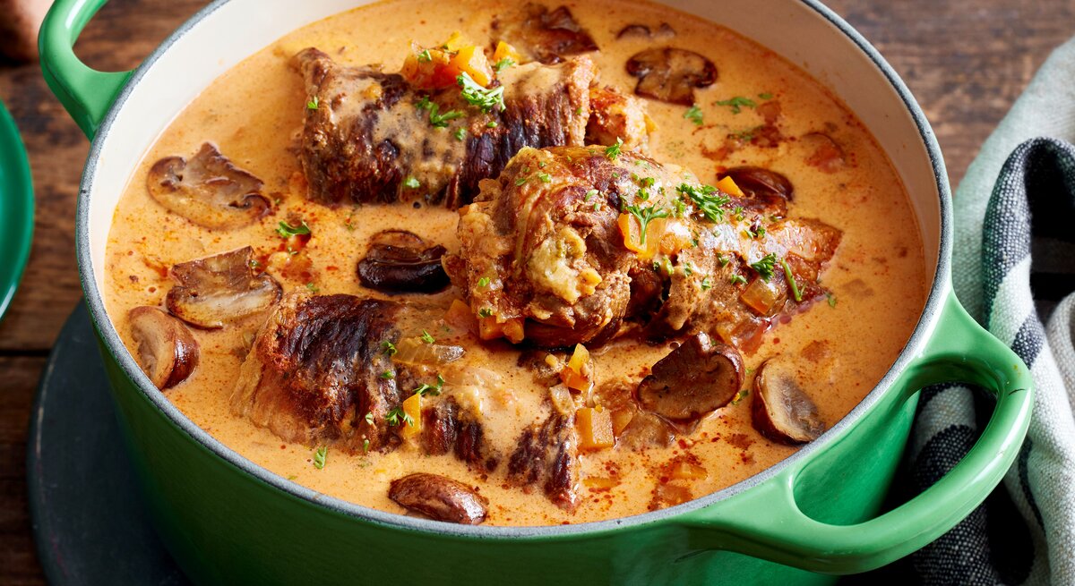 Rindsrouladen mit Knödelmix / gusseiserner Topf / Draufsicht schräg / Untergrund aus Holz