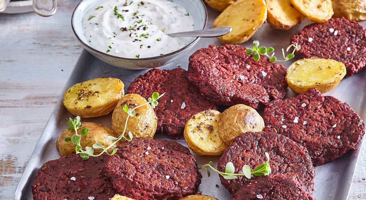 Rote-Bete-Frikadellen mit Kartoffeln auf Tisch serviert.