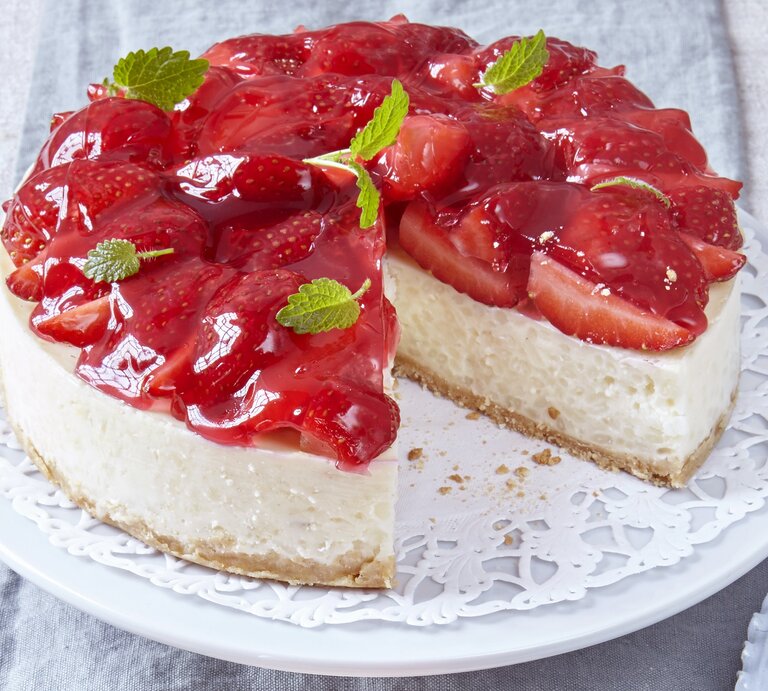 Angeschnittene Milchreistorte mit Erdbeeren und Minzblättern / runde Kuchenplatte / Nahaufnahme Draufsicht | © Carolin Müller
