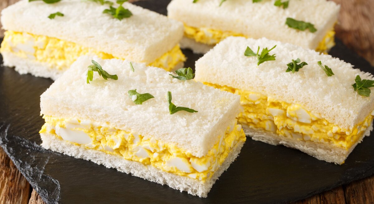 Japanisches Eiersalat-Sandwich auf Schieferplatte auf Holztisch. Draufsicht.
