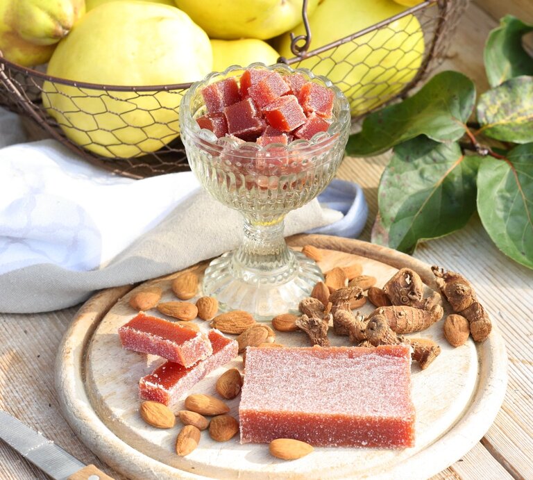 Quittenbrot am Stück und in Würfel geschnitten / Holzbrettchen / frische Quitten / Untergrund Holz / Draufsicht schräg | © StockFood/Raider
