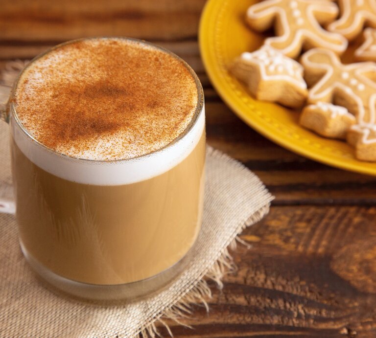 Eine Tasse mit Spekulatius-Latte auf einem Holztisch und einem gelben Teller im Hintergrund. | © AdobeStock/pamela_d_mcadams