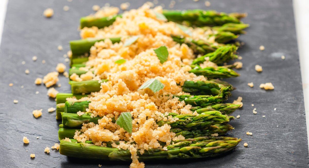 Spargel mit Parmesan-Semmelbröseln auf Schieferplatte.