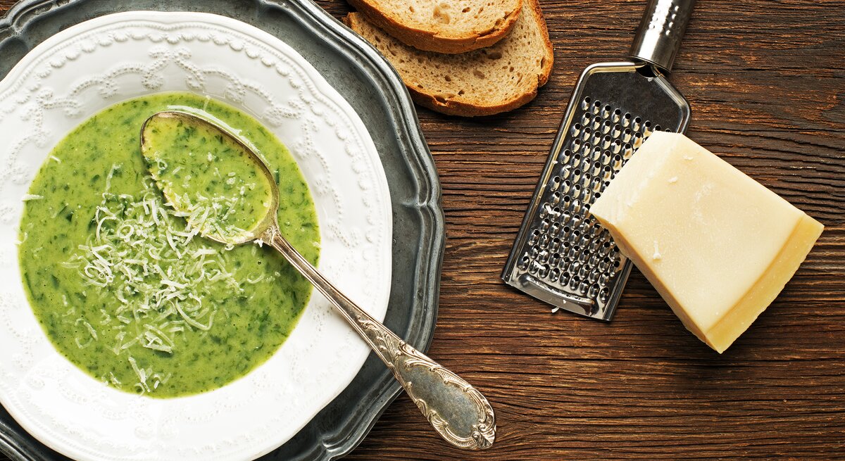 Mangoldsuppe mit frisch geriebenen Parmesan und zwei Scheiben Brot.