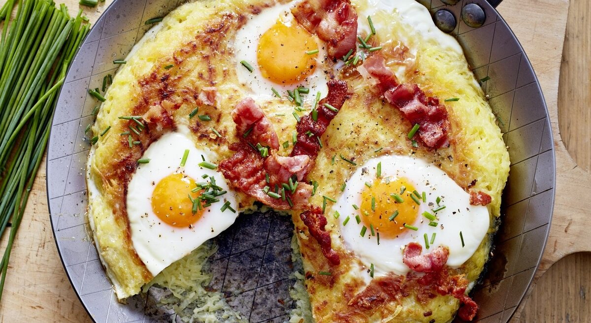 Auf einem Teller liegen Rösti mit Spiegelei. Die sind mit Schnittlauch garniert. 