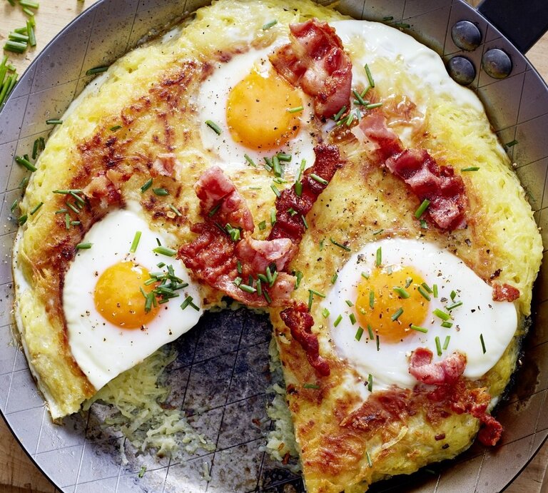 Auf einem Teller liegen Rösti mit Spiegelei. Die sind mit Schnittlauch garniert.  | © EAT CLUB / Isabell Triemer