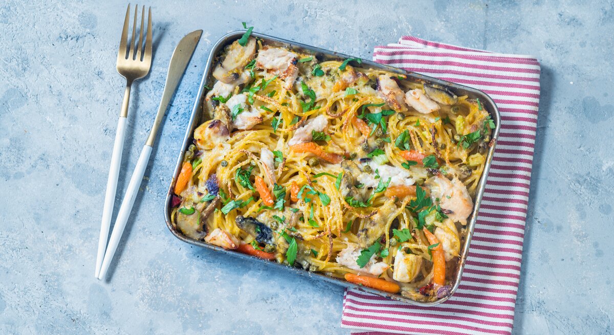 Ein-Blech-Pasta mit Hähnchen: ein Backblech mit Spaghetti, Hähnchen, Pilzen, Möhren und Petersilie.