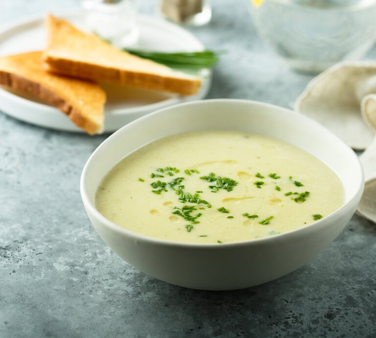 Eine weiße Schale mit der grünen Suppe auf bläulichem Untergrund. Alles von der Seite fotografiert. | © Shutterstock/ MariaKovaleva