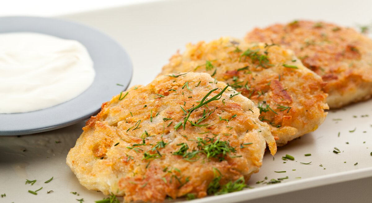 Kartoffel-Käse-Puffer mit Dip auf weißem Teller. 