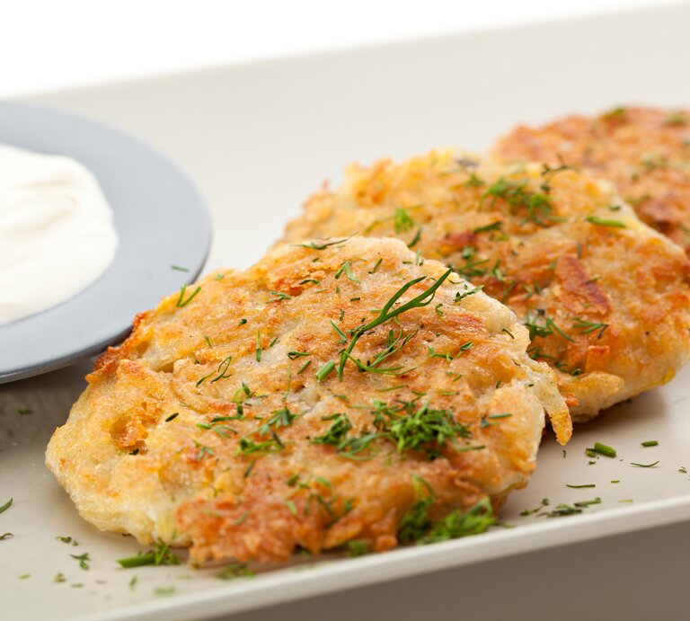 Kartoffel-Käse-Puffer mit Dip auf weißem Teller.  | © Getty Images/Ryzhkov
