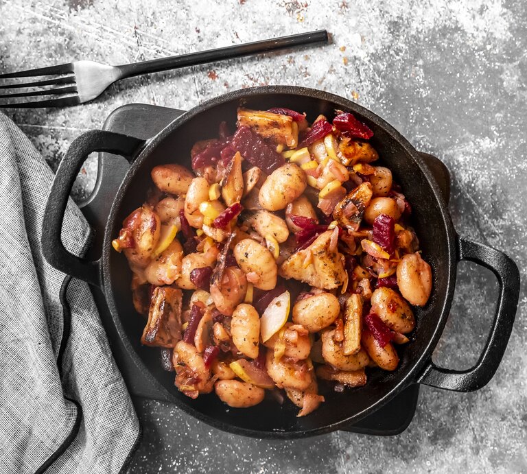 Gnocchi-Pfanne mit roter Bete, Huhn und Birne in gusseiserner Pfanne auf grauem Untergrund.  | © Getty Images/lacaosa