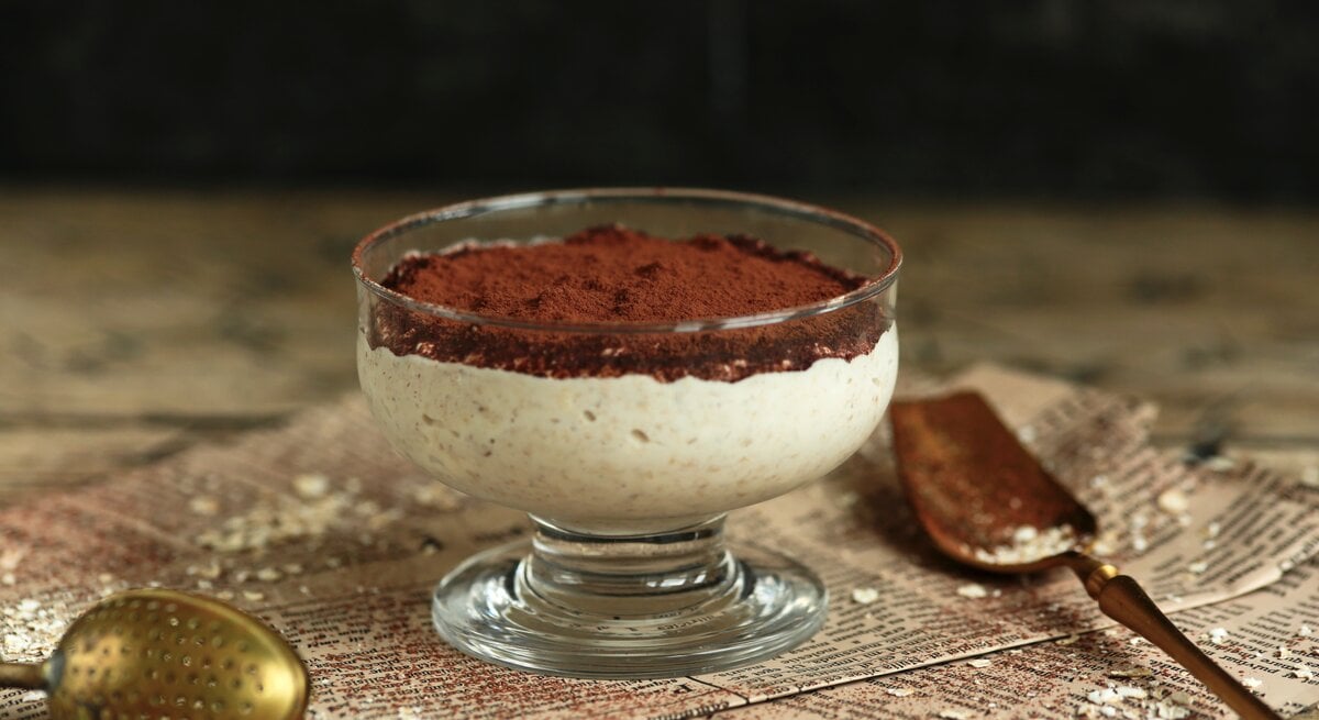 Ein Dessertglas mit Tiramisu-Porridge auf Zeitungspapier.