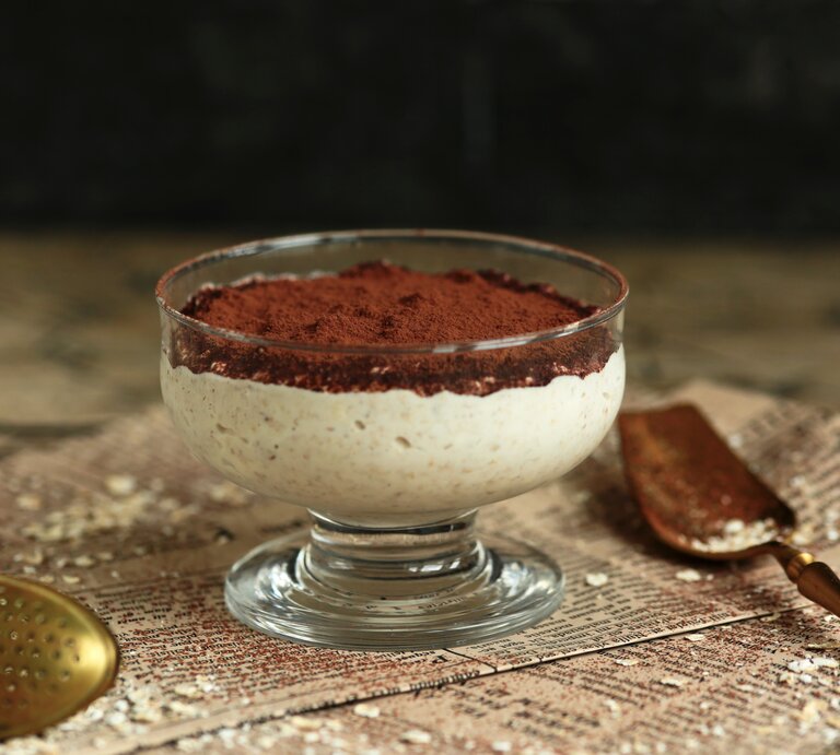Ein Dessertglas mit Tiramisu-Porridge auf Zeitungspapier. | © Shutterstock / Joanna 12