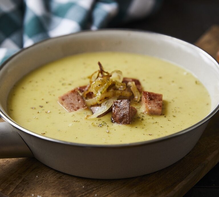 Auf einem Tisch steht eine Pfanne mit einer Kartoffelsuppe mit gebratenem Leberkäse. Sie sieht würzig und aromatisch aus.  | © StockFood / Kirchherr, Jo