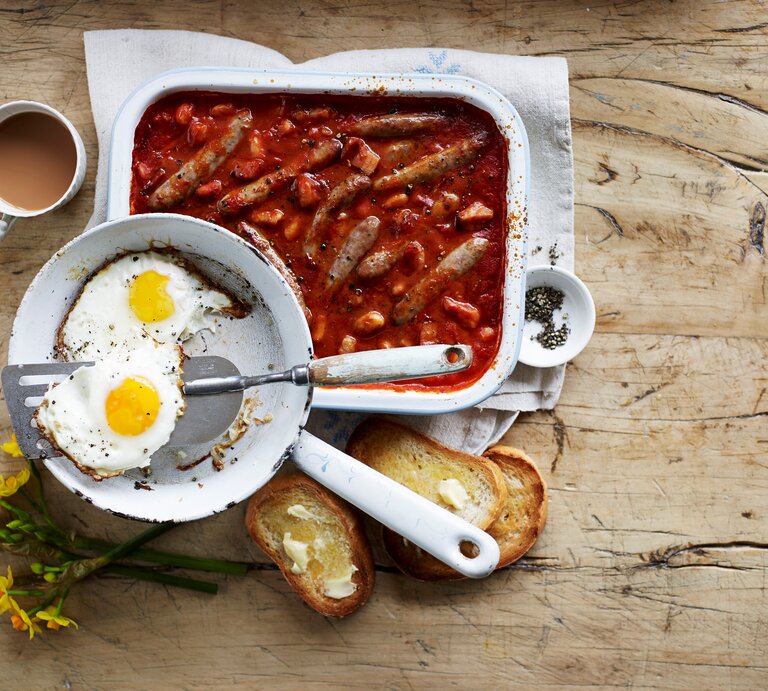 Wurstauflauf mit Bohnen und Speck in Tomatensoße, serviert mit krossen Spiegeleiern und frisch getoasteten Brioche-Scheiben.  | © Eat Club / Isabell Triemer