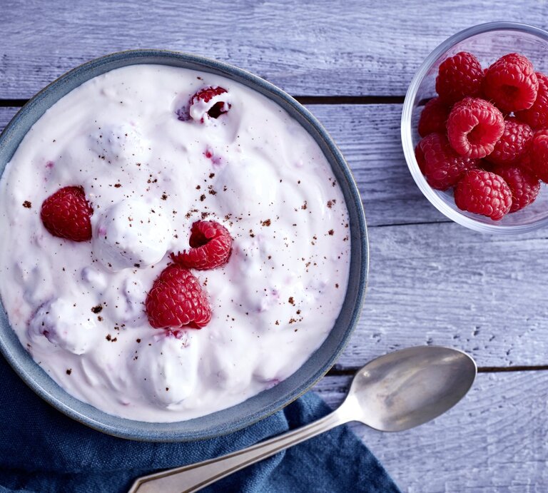 Himbeer-Traum in einer Schale, bestehend aus  Zitronenabrieb, Himbeeren, Honig und griechischem Joghurt, serviert auf einem hölzernen Frühstückstisch.  | © EAT CLUB / Johannes Reinecke